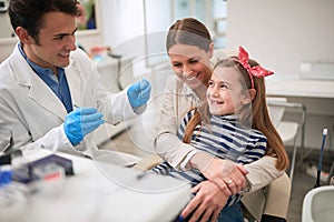 Family in dentistÃ¢â¬â¢s office.dentist examining his girl patient in dentistÃ¢â¬â¢s clinic photo