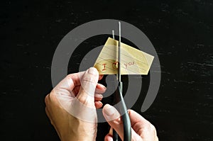 Family divorce. Cropped image of hand cutting paper family with scissors over wooden table