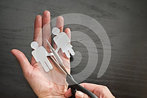 Family divorce. Cropped image of hand cutting paper family with scissors over wooden table