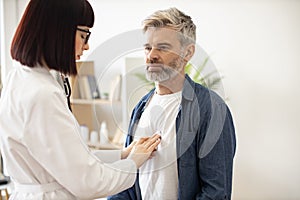 Family doctor checking lungs of man via stethoscope