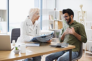 Family doctor examining diagnostic test results while developing treatment plan.