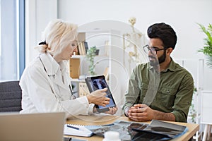 Family doctor examining diagnostic test results while developing treatment plan.