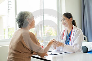 Family doctor examining smiling asian old woman using stethoscope at hospital An old woman talks