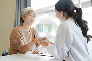 Family doctor examining smiling asian old woman using stethoscope at hospital An old woman talks