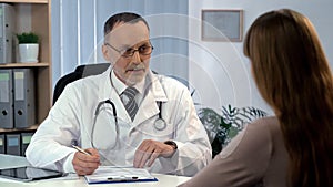 Family doctor listening to patient, filling out medical insurance, health care