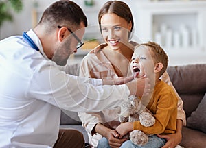 Family doctor pediatrician conducts examination of   child boy with his mother, looks at his throat