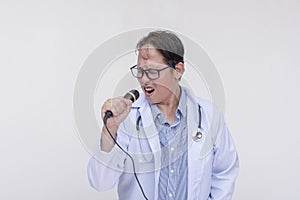 A family doctor singing with a microphone during a karaoke session after work. Of asian descent, middle aged male in his 40s.