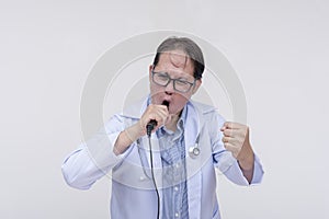 A family doctor singing with a microphone during a karaoke session after work. Of asian descent, middle aged male in his 40s.