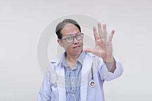 A family doctor tells to stop with his open palm. Forbidding certain foods or medication. Of asian descent, middle aged male in
