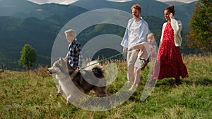 Family dog spending holiday in summer mountains. Parents with kids walking pet.