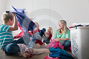 Family doing laundry at home, mother with kids have fun while sorting clothes