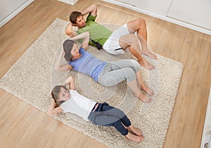 Family Doing Situps On Rug At Home