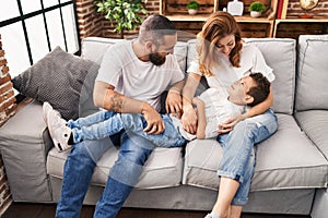 Family doing tickle to son sitting on sofa at home