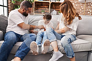 Family doing tickle to son sitting on sofa at home