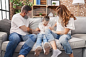 Family doing tickle to son sitting on sofa at home