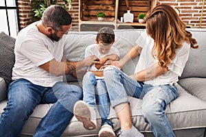 Family doing tickle to son sitting on sofa at home