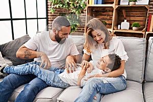 Family doing tickle to son sitting on sofa at home