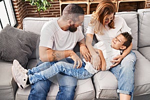 Family doing tickle to son sitting on sofa at home