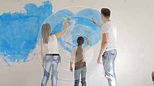 Family draw heart on a wall with a blue paint. Happy day concept