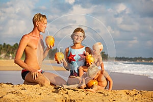 Family drink cocnut at the beach at sunset
