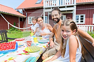 Family drinking coffee and eating cake front of house