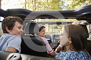 Family Driving In Open Top Car On Countryside Road Trip