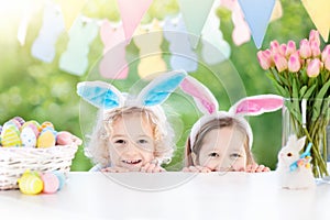 Kids with bunny ears and eggs on Easter egg hunt.