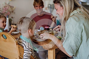 Family eating breakfast together in home kitchen. Healthy breakfast or snack before school and work. Mother helping