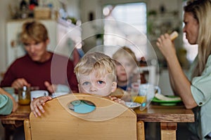 Family eating breakfast together in home kitchen. Healthy breakfast or snack before school and work. Mother helping