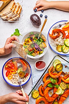 Family eating a healthy vegetarian food. Vegan lunch table top view, plant based diet. Baked vegetables, fresh salad, berries,