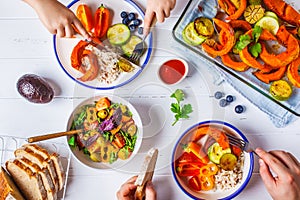 Family eating a healthy vegetarian food. Vegan lunch table top view, plant based diet. Baked vegetables, fresh salad, berries,