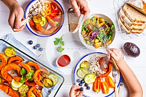 Family eating a healthy vegetarian food. Vegan lunch table top view, plant based diet. Baked vegetables, fresh salad, berries,