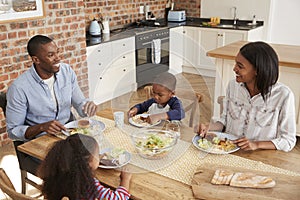 Family Eating Meal In Open Plan Kitchen Together