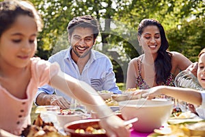 Family Eating Outdoor Meal In Garden At Home Together