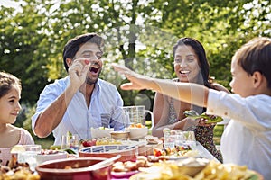 Family Eating Outdoor Meal In Garden At Home Together