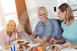 The family eats at the festive table for Thanksgiving. People are communicating