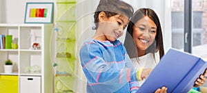 happy mother and daughter reading book at home