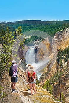 Family embracing and enjoying beautiful view of waterfall on hiking trip in the mountains.