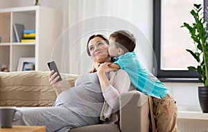 Son kissing happy pregnant mother at home