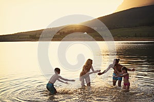 Family Enjoying Evening Swim In Countryside Lake