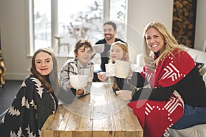 Family Enjoying Hot Drink In Cafe at home close to fireplace