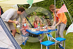Family Enjoying Meal Outside Tent On Camping Holiday
