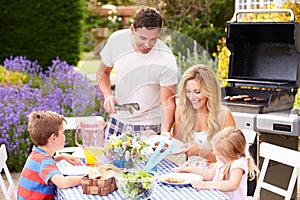 Family Enjoying Outdoor Barbeque In Garden photo