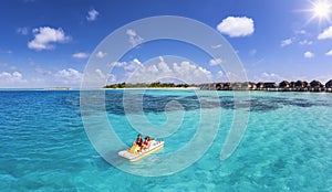 A family enjoying a pedalo boat ride over the turquoise ocean of the Maldives islands