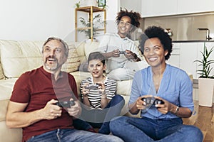 Family enjoying time together at home sitting on sofa in living room and playing video games