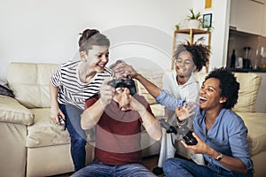 Family enjoying time together at home sitting on sofa in living room and playing video games