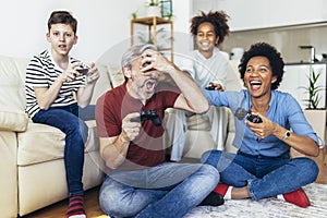 Family enjoying time together at home sitting on sofa in living room and playing video games