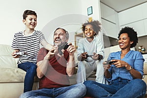 Family enjoying time together at home sitting on sofa in living room and playing video games