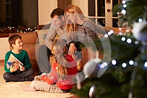 Family Exchanging Gifts By Christmas Tree