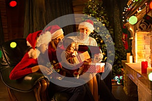 Family exchanging gifts in front of fireplace at Christmas tree